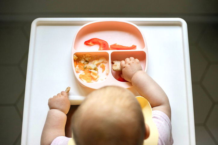 Overhead view of infant baby eating in the table for feeding.
