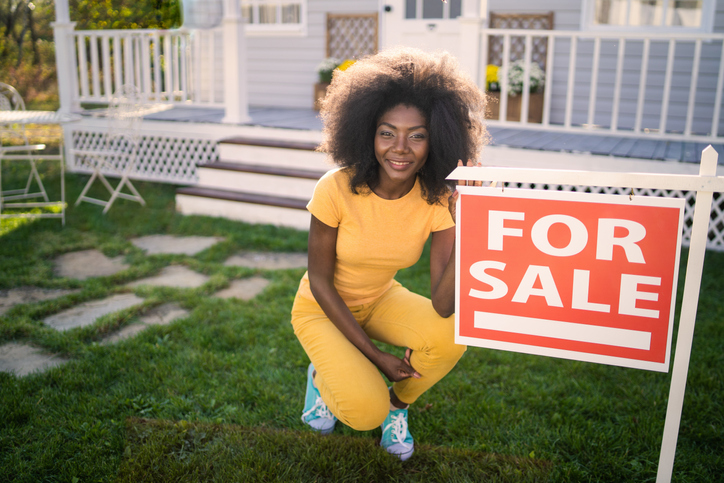 For Sale sign with woman squatting beside