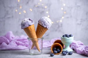 Blueberry ice cream cones with fairy lights on concrete background