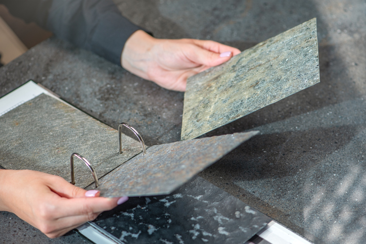 Samples of artificial stone in hands close-up. Natural stone veneers for finishing interior elements and furniture.