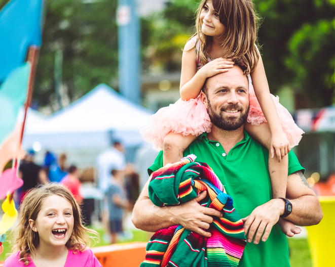 Father with two kids at an outdoor summer carnival festival fair or amusement park, family fun