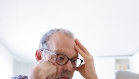 Stressed and disappointed senior caucasian man using laptop at home feeling overwhelmed. Vertical image.