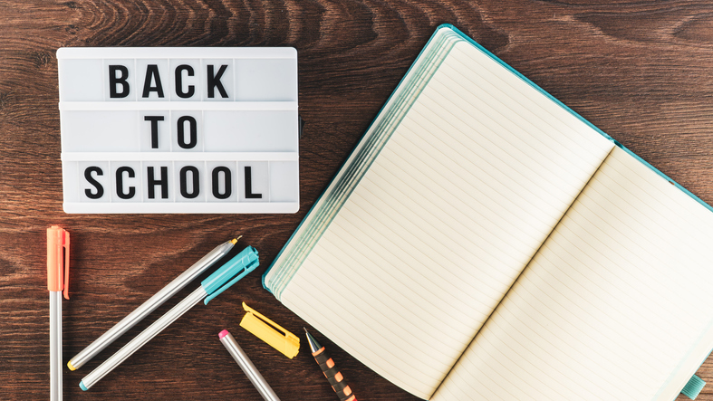 Back to school concept. School supplies on wooden background. Back to school lettering on white letter board. Copy space for text. Selective focus included