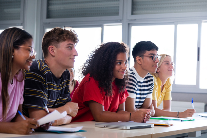 Black female high school student in class with multiracial classmates. African american college student in class.