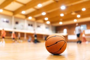 Basketball Ball on Wooden Court. Basketball Game in the Blurred Background. Basketball Court Background. Classic SPorts Basketball Ball