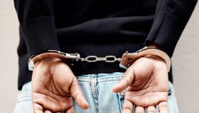 Man, handcuffs and criminal in arrest for crime, justice or theft against the wall of suspect. Closeup of male person, gangster or thief in corruption, violence or fraud for jail, prison or locked up