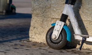 Electric hireable scooter standing against wall in urban downtown scene