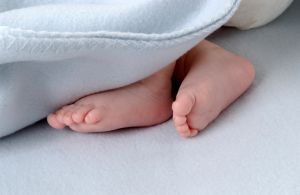 Small, newborn baby feet close up under a blanket