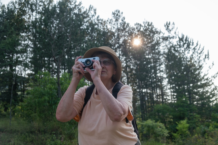 Senior woman in the mountains photographing with a vintage photo camera