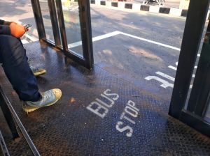 Bus passengers are using their cell phones while waiting for the bus at the bus stop