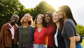 Young multiracial women having fun outdoor - Diverse female friends hugging each other during summer vacations at city park - Focus on center faces