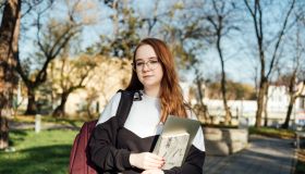 Understanding Student Loan Repayment Options. Pros and Cons of Federal vs Private Student Loans. Young student girl in glasses and with laptop and books reading letter outdoors