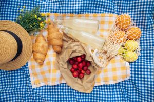 Picnic scene: croissants, strawberries, lemonade on blue blanket.