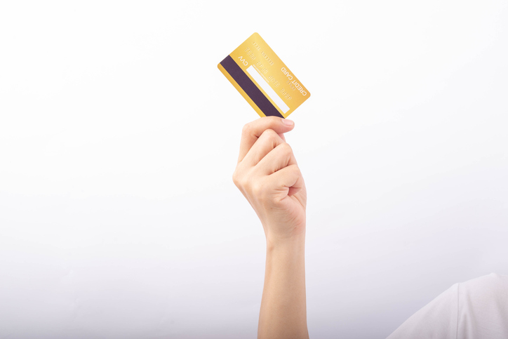 Female hand holding golden credit card showing back on white background.