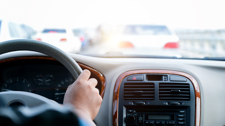 Man hand on steering wheel inside of a car at traffic jam