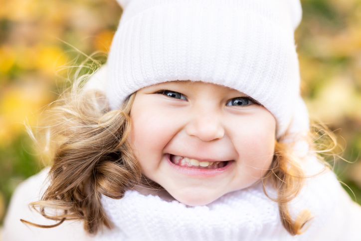 A cute pretty girl is running in the park in the middle of autumn leaves and smiling.