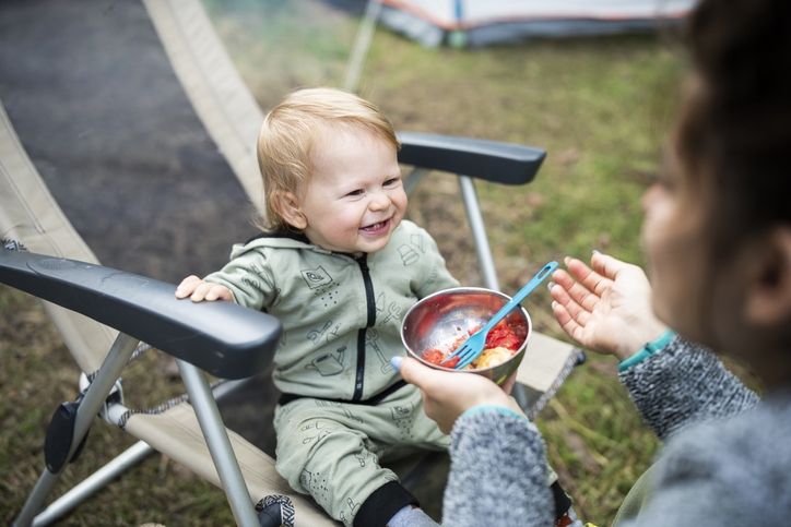 Baby boy eating lunch on camping vacation.