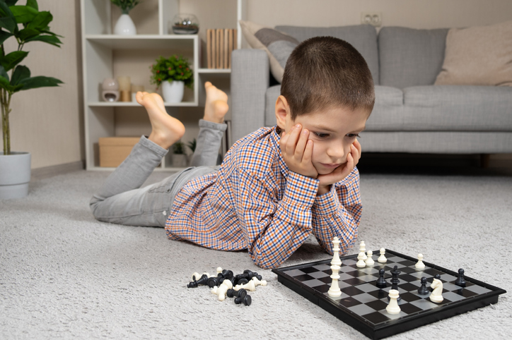 Little boy playing chess. Board games for children