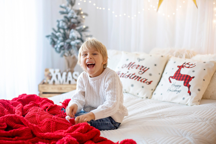 Beautiful blond child, young school boy, playing in a decorated home with knitted toys