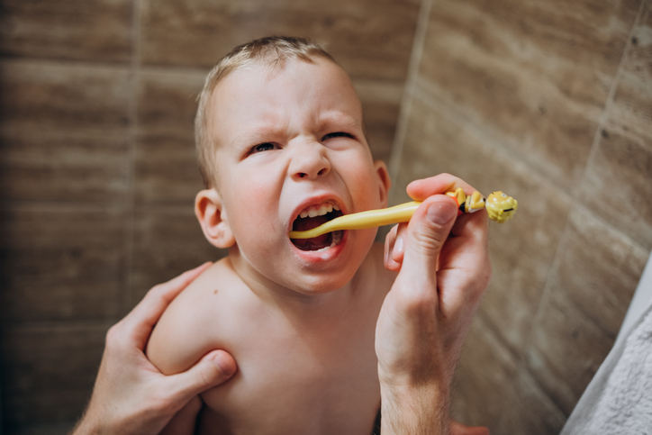 father brushes child's teeth in the morning