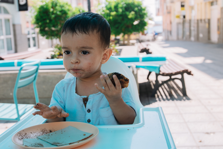 Baby eating a chocolate chip cookie sitting in a highchair