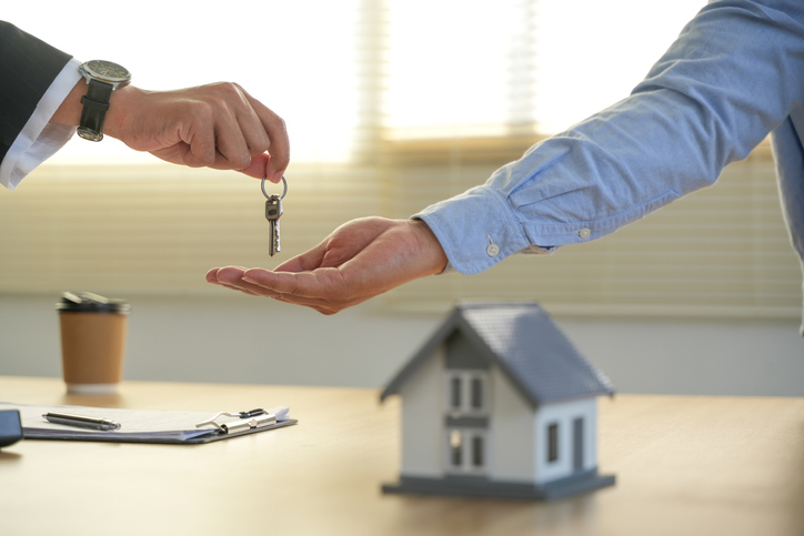 A real estate agent gives a client the house keys after signing a real estate contract with an approved mortgage form. About offering mortgage loans and home insurance.