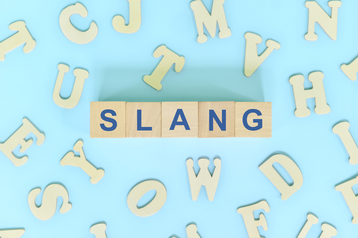 Slang language concept. Wooden blocks typography word flat lay in blue background.