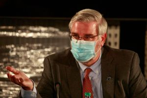 Indiana Governor Eric Holcomb wearing a face mask speaks...