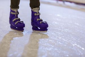 Young man ice skating at the ice rink in the evening