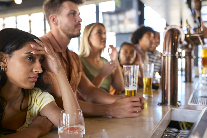 Disappointed Multi-Cultural Group Of Friends In Sports Bar Watching Team Lose Game On TV