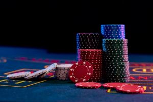Colorful chips piles standing on blue cover of playing table. Black background. Gambling entertainment, poker, casino concept. Close-up.