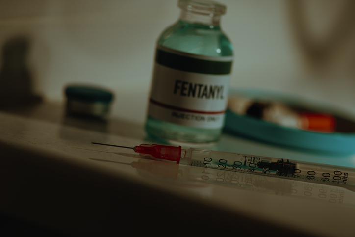 syringe and vial of fentanyl in a sordid bathroom