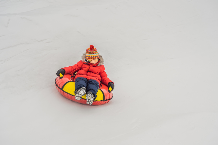 Child having fun on snow tube. Boy is riding a tubing. Winter fun for children