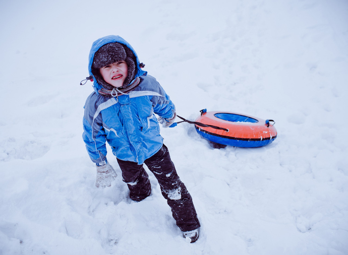 Boy sliding down hill on a snow tube