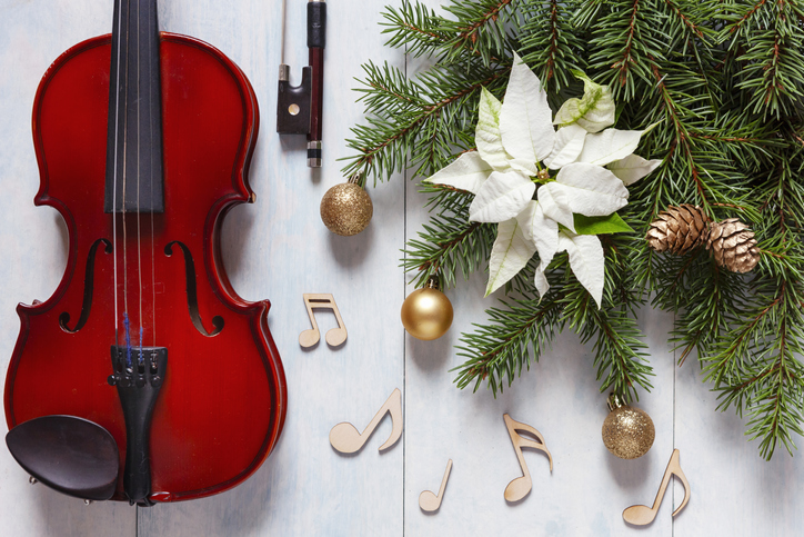 Old violin, wooden notes signs and fir-tree branches with Christmas decor and white poinsettia. Christmas, New Year's concept. Top view, close-up