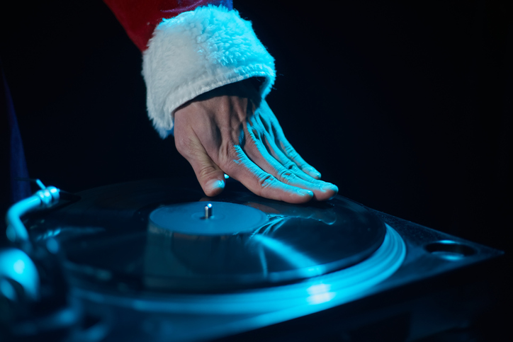 Hip hop DJ in red Santa costume scratching a vinyl record on turntable deck