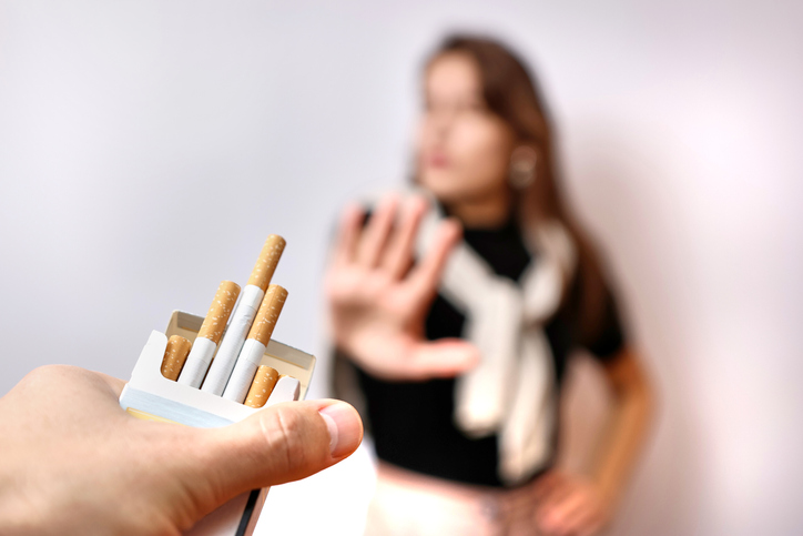 The girl is offered a cigarette, but she refuses, gesturing. The concept of the bad habit of smoking.