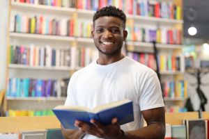 A diligent student in a university library, surrounded by books and bookshelves, engaged in academic learning and research.