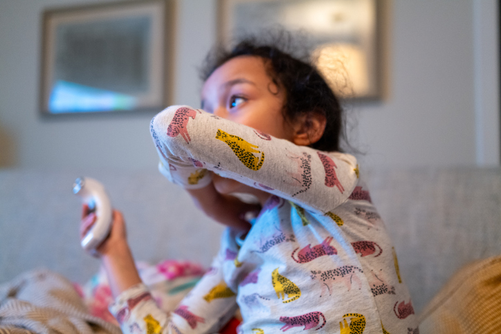 young multiracial girl coughs into her elbow