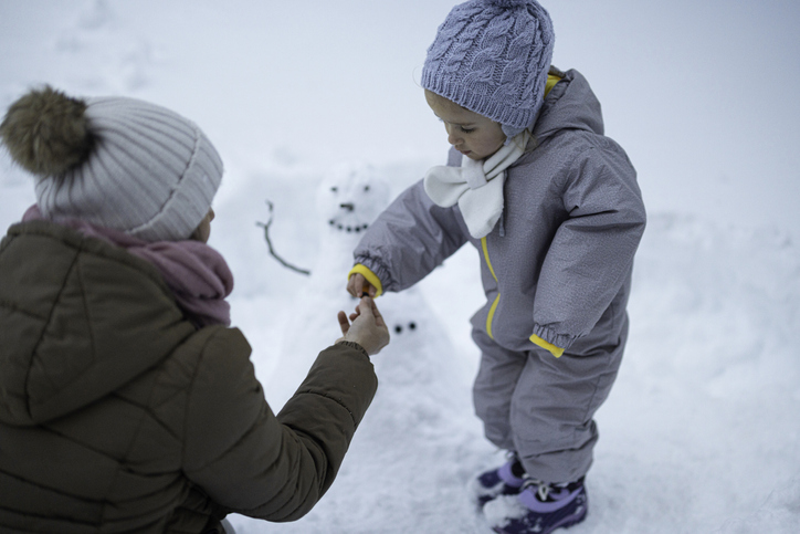 Winter family fun in deep snow. Mom and kid play.