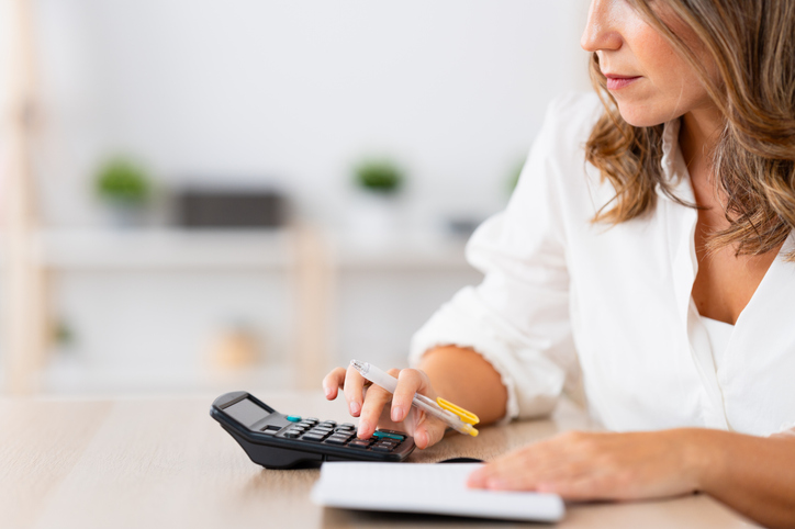 Mature woman preparing home budget using calculator