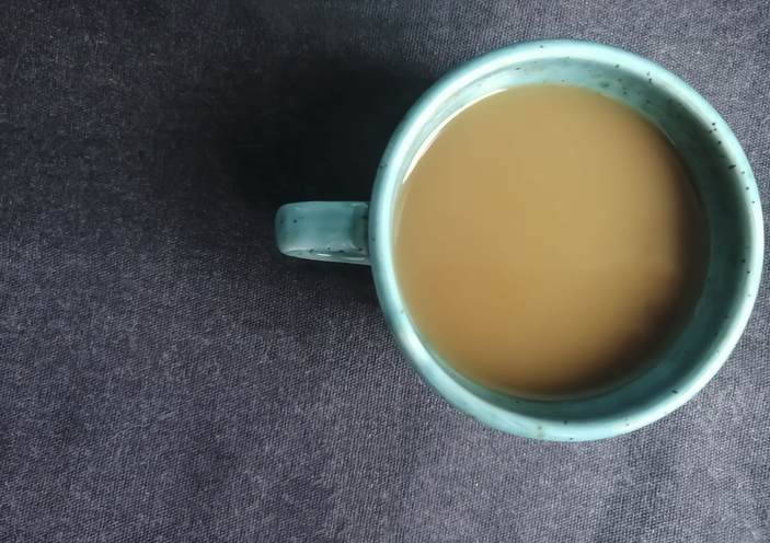 Cup of coffee on a dark background. Shot from above - coffee with milk on a black tablecloth.