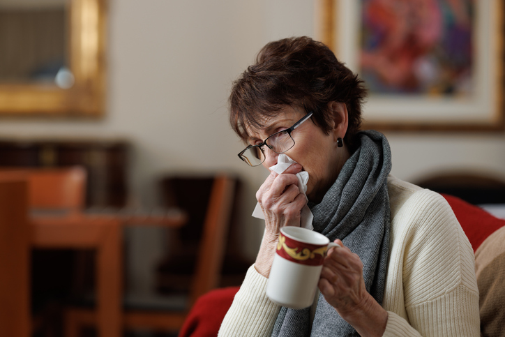 Sick woman at home holding tissue and coffee cup
