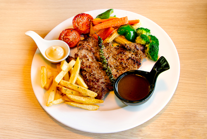 Grilled beef steak with grilled vegetables, carrots, cherry tomatoes, broccoli and French fries. American food concept, copy space