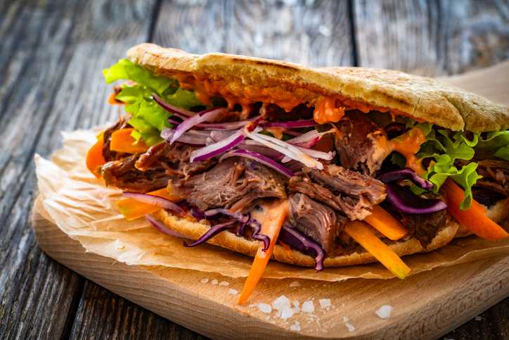Pita - big sandwich with pulled beef and fresh vegetables on wooden table