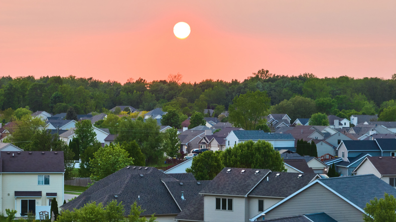Green forest tree skyline aerial of sun rising setting over suburban homes neighborhood houses