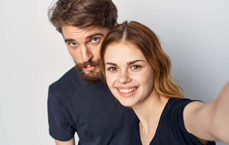 man and woman in black t-shirts with phone chatting fun cropped view Studio