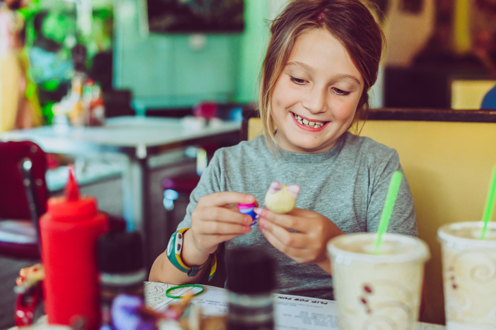 Cute candid kid sitting at a restaurant or diner both for fast casual food