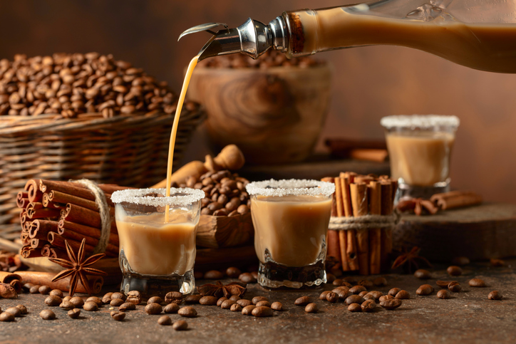 Irish cream and coffee liqueur is poured from a bottle into a glass.