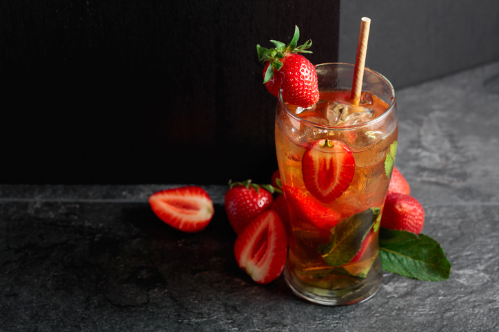 Iced tea or a summer refreshing drink with ice, mint, and strawberries.